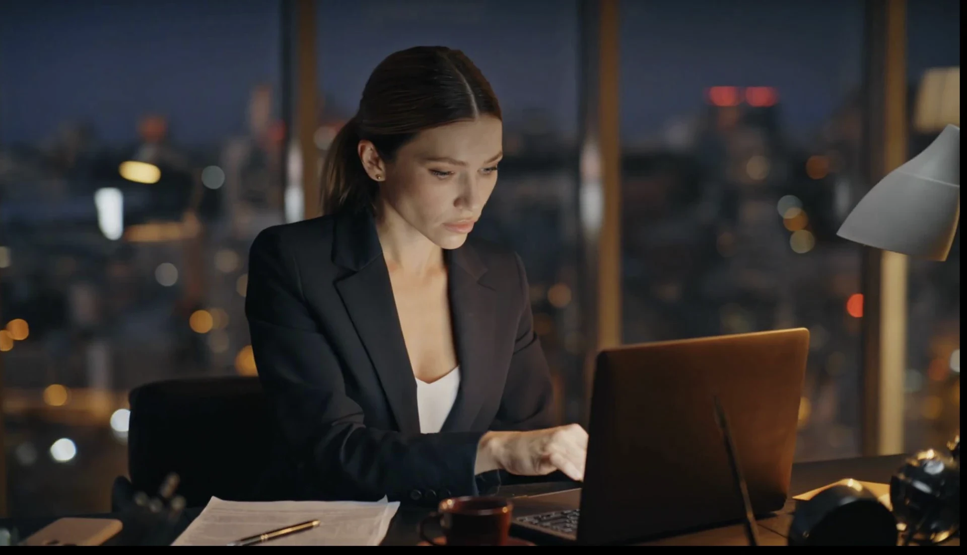 Professional woman working late at a laptop in a city office